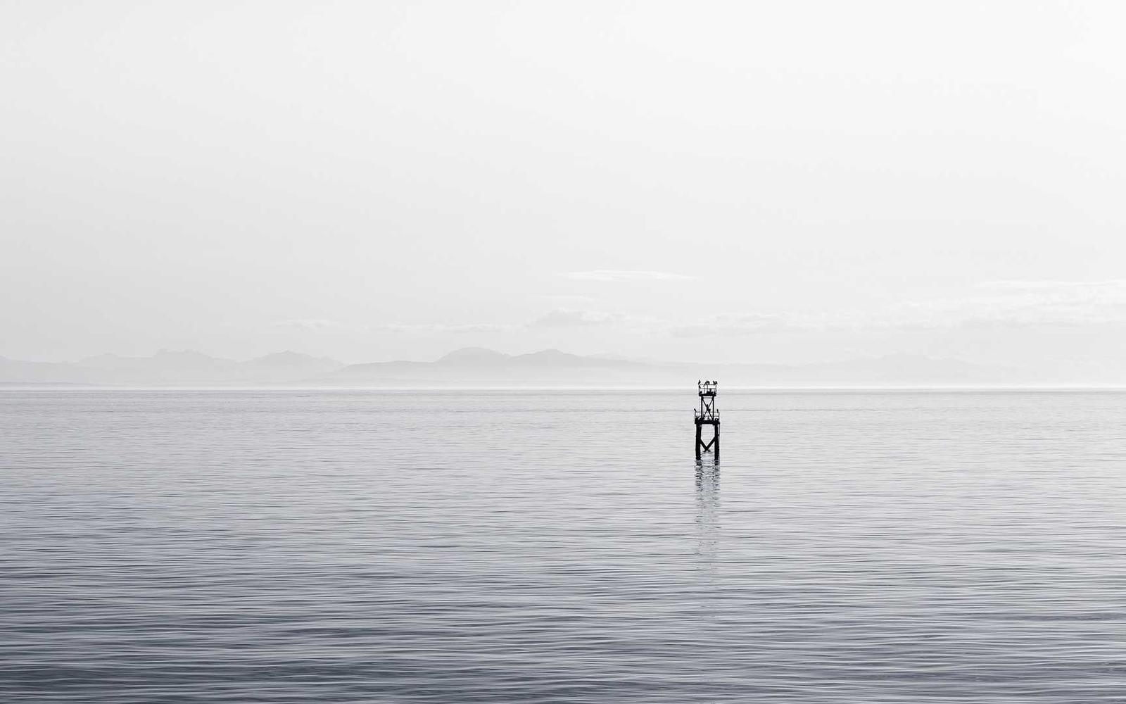 A pale morning sea with a distant marker buoy
